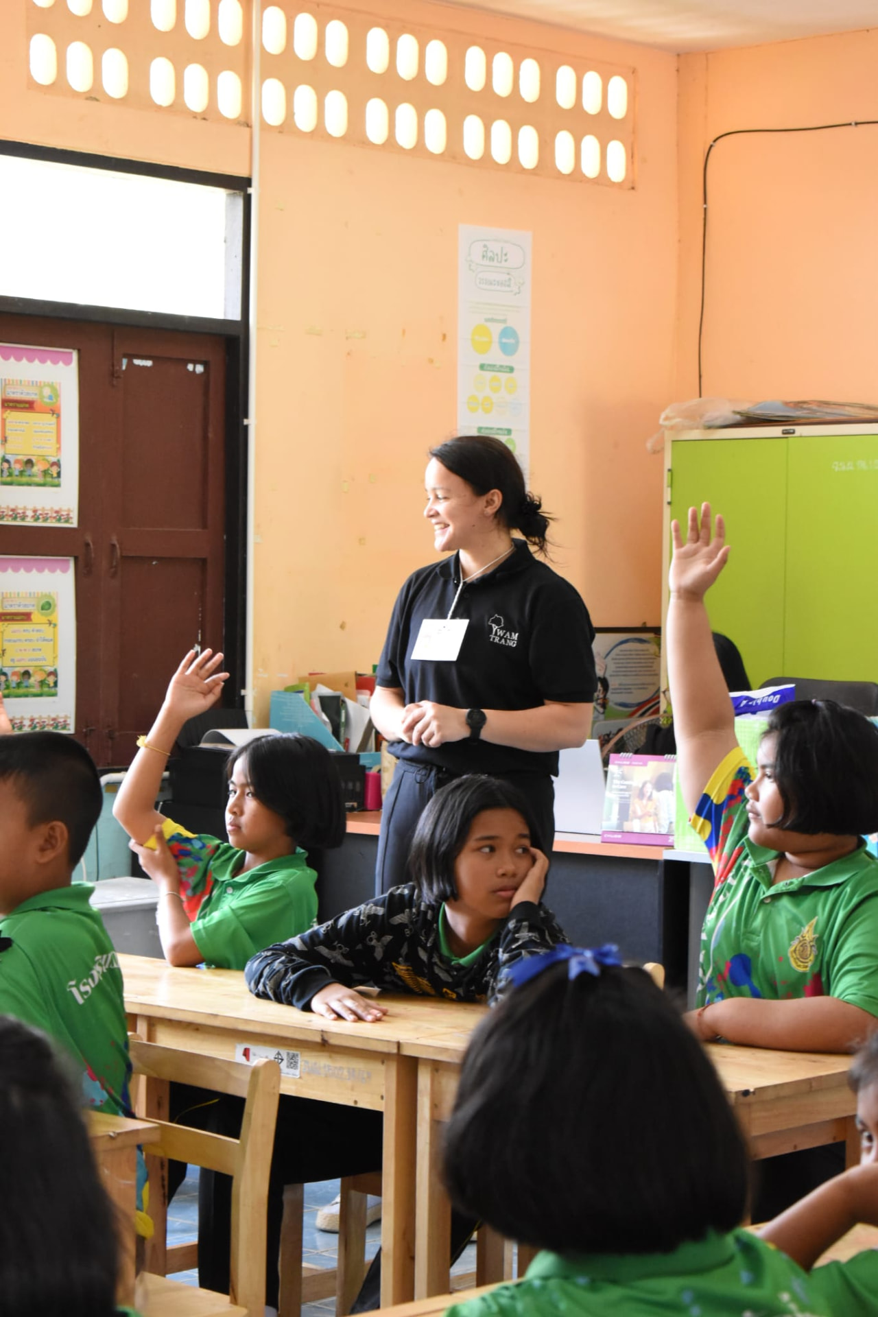 Patricia Holanda ensinando em sala de aula com alunos levantando a mão